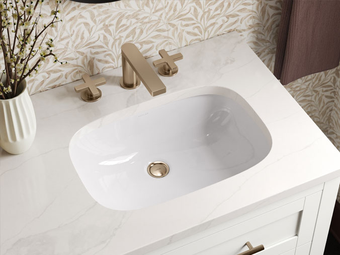 Downward view of bathroom sink and vanity with rose gold faucet and fixtures